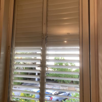 חלון עם תריסים לבנים פתוחים חלקית