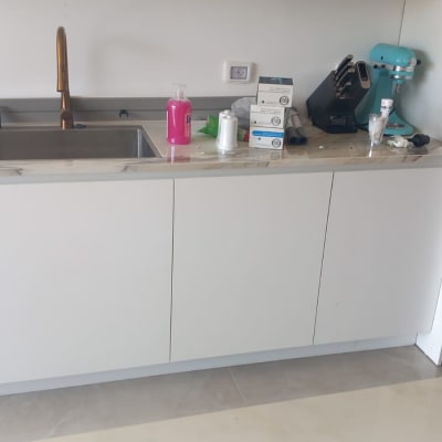 מטבח עם כיור, ברז, מכונת קפה ומוצרים שונים על השיש