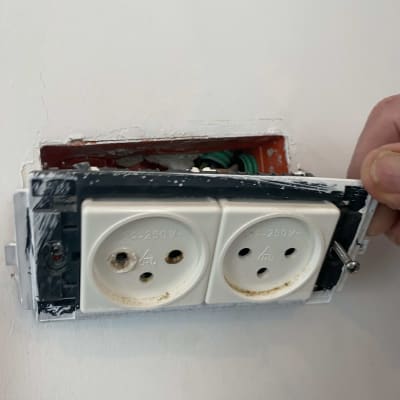 שקע חשמלי כפול מותקן בקיר עם חוטים חשופים