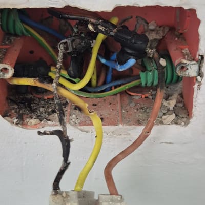 חוטי חשמל שרופים בתוך קופסת חיבורים בקיר