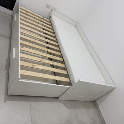 מיטה לבנה עם מסגרת עץ בחדר ריק