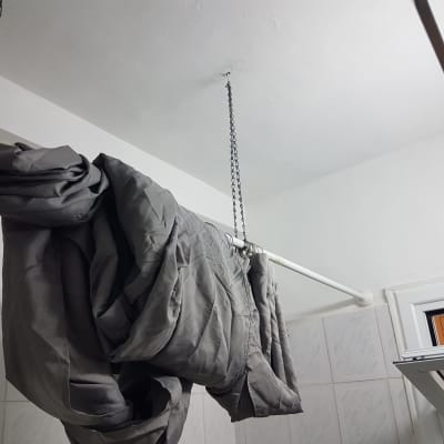 מעיל אפור תלוי על מוט בחדר