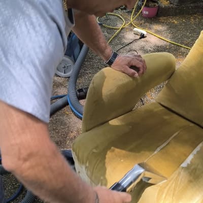 אדם מנקה כיסא עם מכונת ניקוי