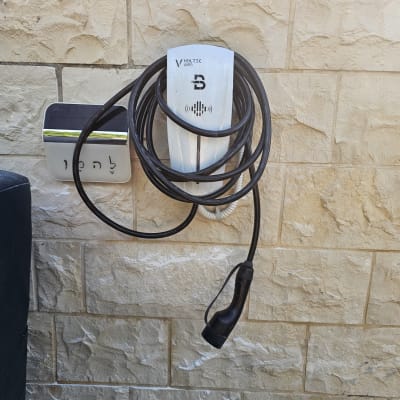 מטען לרכב חשמלי תלוי על קיר עם כבל ארוך