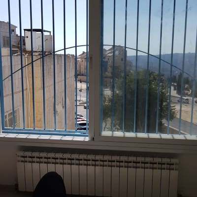 חלון עם סורגים כחולים ומסגרת לבנה