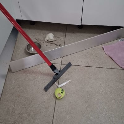 מגב אדום על רצפה עם כדור טניס