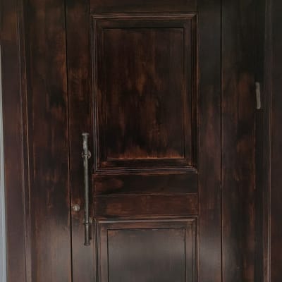 דלת עץ כהה עם ידית מתכת על רצפת אבן
