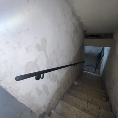 מעקה מתכת שחור לאורך גרם מדרגות בטון