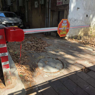 שער חשמלי עם שלט אדום ושלט עם שם העסק