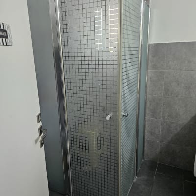 מקלחון עם דלת זכוכית מרובעת וראש מקלחת