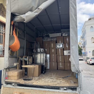 משאית פתוחה עם קרטונים וציוד מעבר ברחוב עירוני
