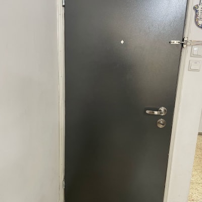 דלת מתכת אפורה עם ידית ומנעול כסופים