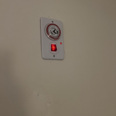 מתג טיימר על קיר עם נורית חיווי אדומה