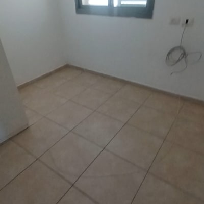 חדר ריק עם רצפת אריחים וחלון עם תריסים