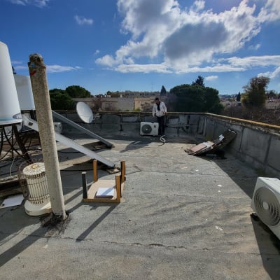 אדם עובד על מזגן על גג עם שמיים בהירים