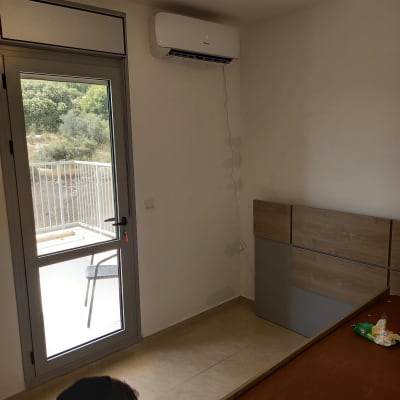 מזגן מותקן על קיר בחדר עם חלון ודלת