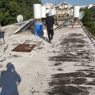 אדם על גג עם דליים וחומרי איטום