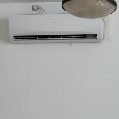 מזגן מותקן על קיר לבן ליד מנורה תלויה