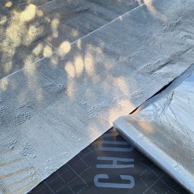 גג מכוסה בחומר מבודד כסוף עם כיתוב על יריעה שחורה