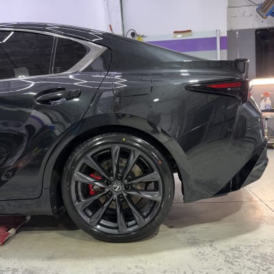 רכב שחור עם גלגלים מבריקים בסדנת דיטיילינג