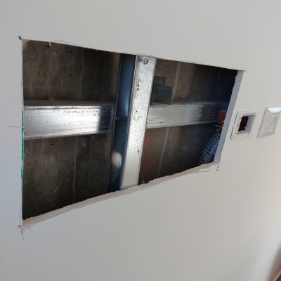 קיר פתוח עם מסגרת מתכת וחוטי חשמל