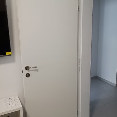 דלת לבנה עם ידית מתכת כסופה פתוחה למחצה