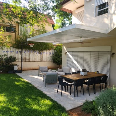 פרגולה מאלומיניום בחצר עם שולחן וכיסאות