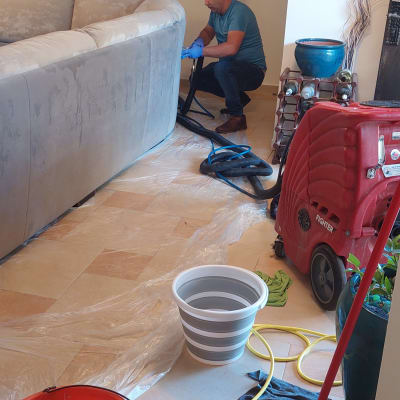 אדם מנקה ספה עם מכונת ניקוי ואביזרים