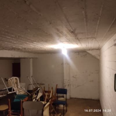 חדר עם קירות לבנים מתקלפים ותקרה חשופה