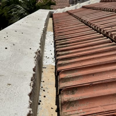 גג רעפים אדומים עם תעלה לבנה בצד