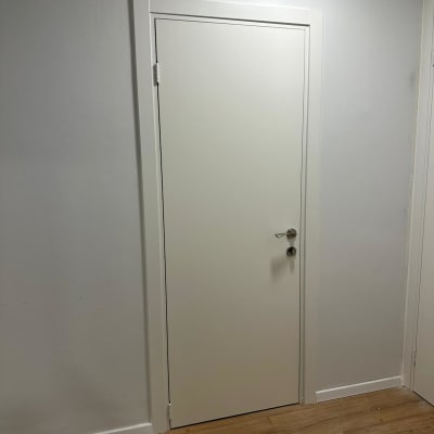 דלת לבנה עם ידית מתכת על קיר לבן