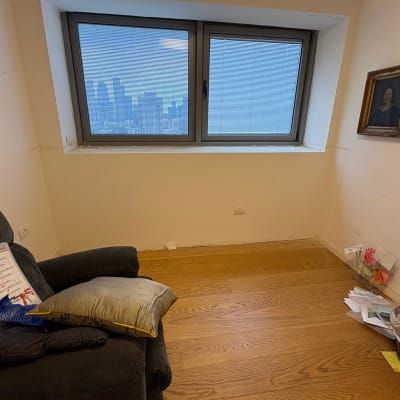 חדר עם כורסה, חלון ונוף עירוני, מסמכים בפינה