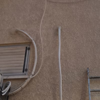 צינורות חיצוניים על קיר בניין עם סולם בצד