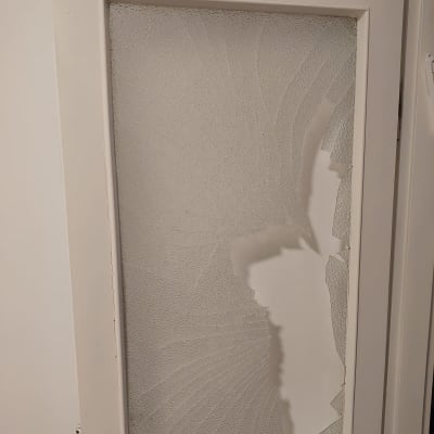 דלת עם זכוכית שבורה וסדוקה בחלקה התחתון