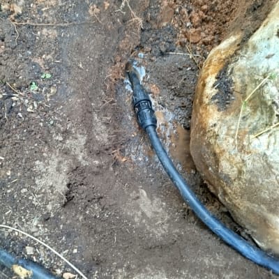 צינור מים דולף באדמה ליד סלע