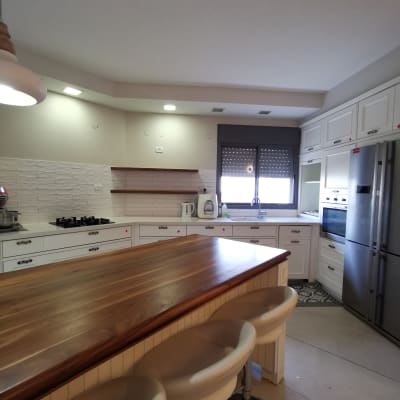 מטבח מאורגן עם אי עץ, כיסאות, מקרר ותנור