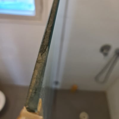 זכוכית מקלחון עם ידית עץ ומקלחת ברקע