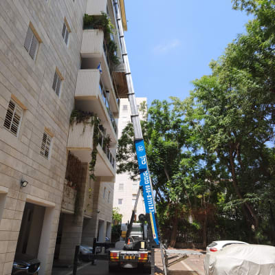 מנוף ליד בניין מגורים עם עצים מסביב