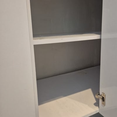 ארון פתוח עם מדפים ריקים על רצפה מאובקת