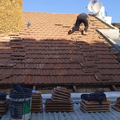 עובד על גג רעפים עם כלים ואריחים