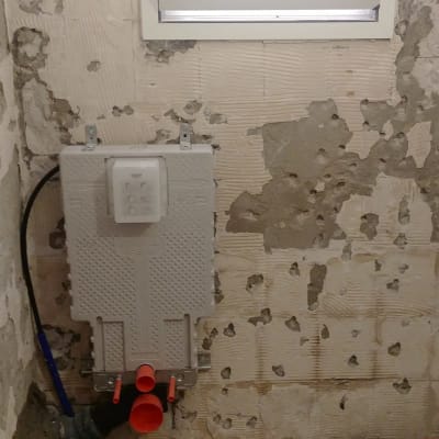 קיר חשוף עם צנרת ושקע חשמל במהלך שיפוץ