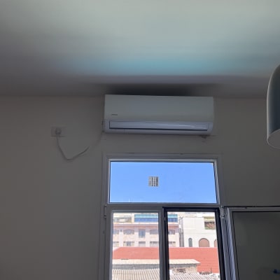 מזגן מותקן על קיר מעל חלון פתוח
