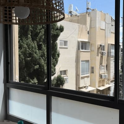 חלון אלומיניום עם נוף חיצוני ועץ ירוק