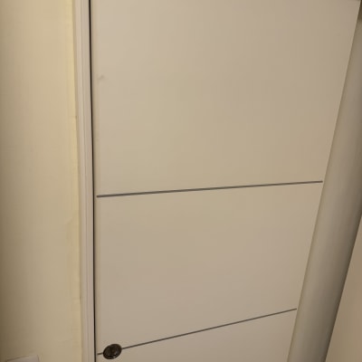 דלת לבנה עם ידית עגולה וקיר צמוד