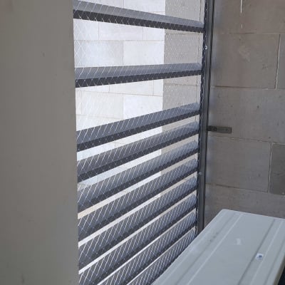 רשת מתכת מותקנת על חלון למניעת כניסת יונים