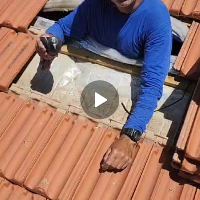 אדם עובד על גג רעפים עם כלי עבודה ביד