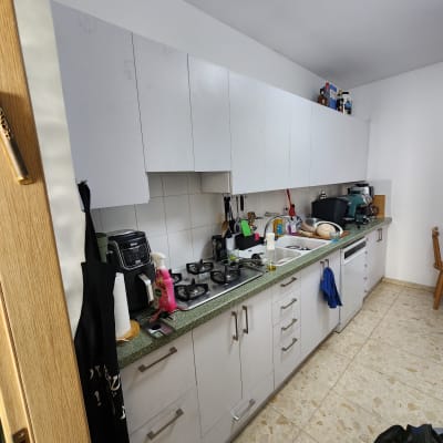 מטבח עם ארונות לבנים ומשטח עבודה ירוק