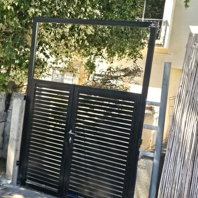 שער מתכת שחור עם צמחייה ברקע
