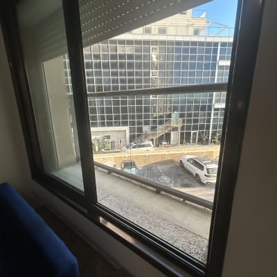 נוף עירוני מבעד לחלון עם בניין זכוכית ומכוניות