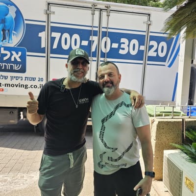 שני אנשים עומדים ליד משאית עם לוגו של חברת הובלות